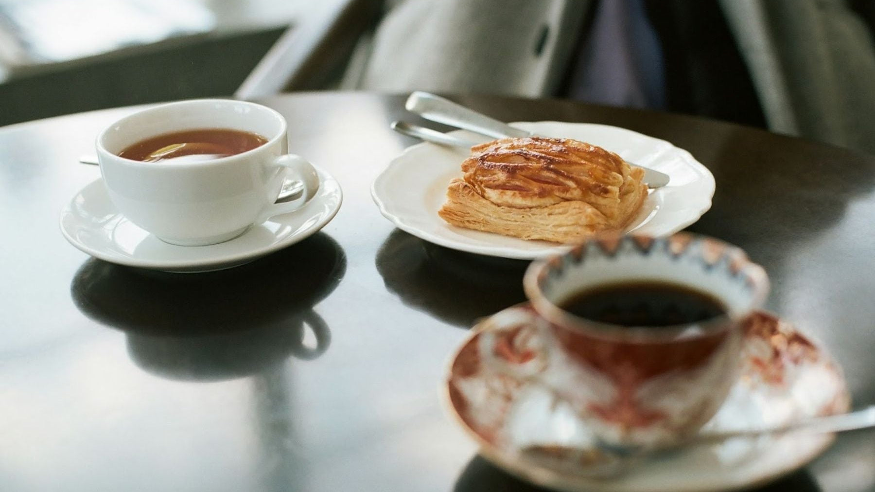 Two cups of English Breakfast tea served alongside a pastry