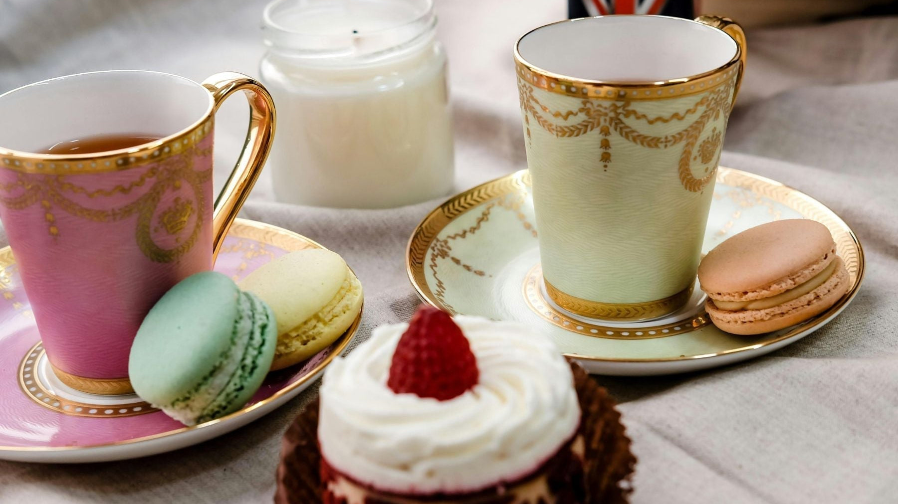 Elegant tea cups with macarons and cupcake in a cozy tea setting
