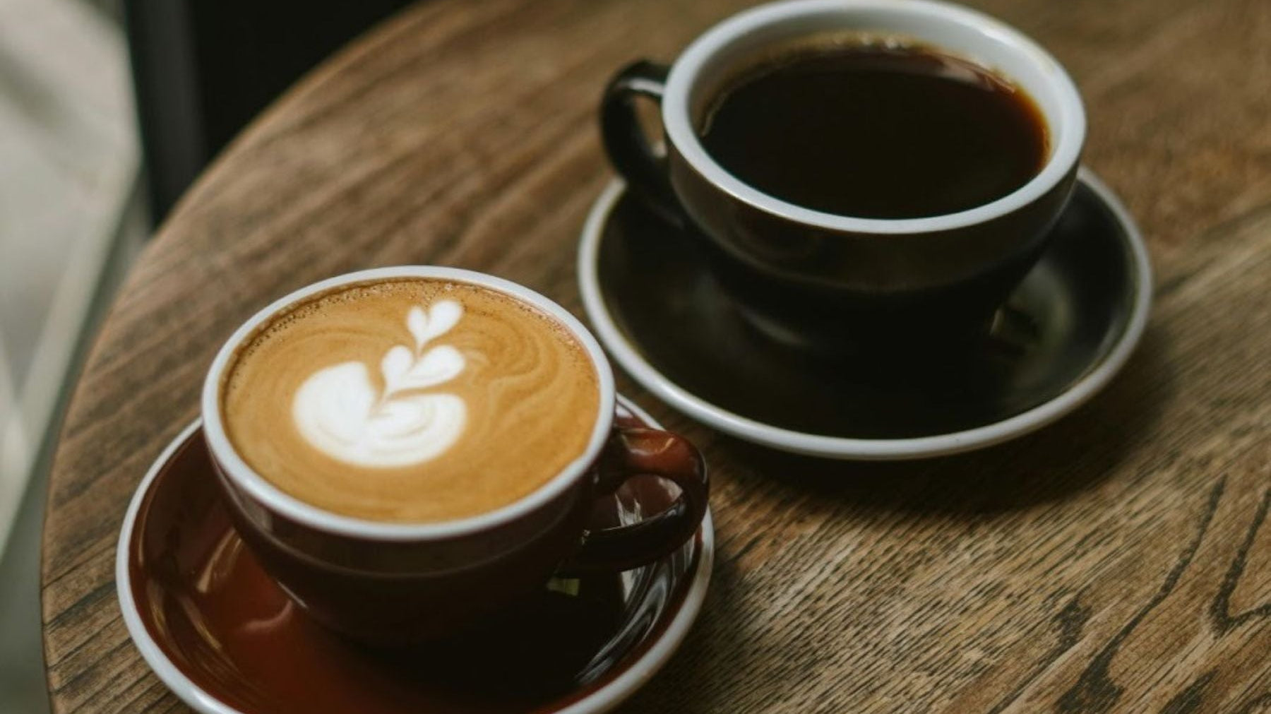 Coffee and black tea cups on a wooden table