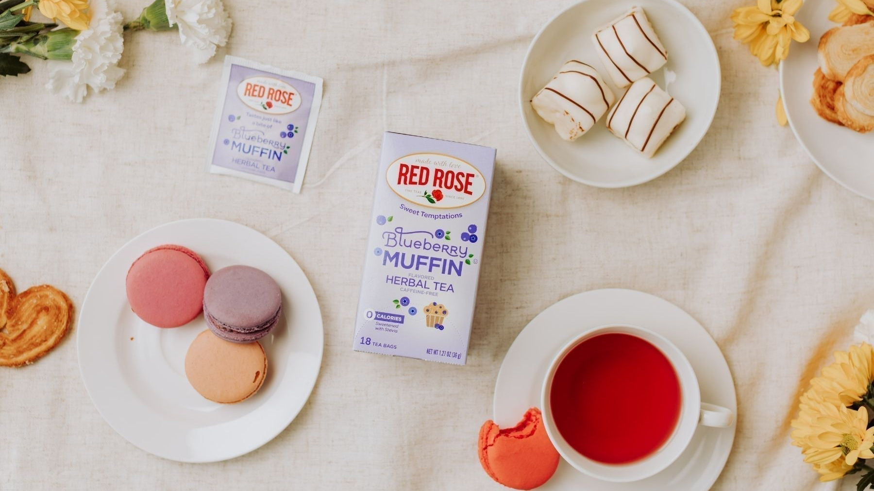 Blueberry muffin tea box with macarons, pastries, and tea in a flat lay