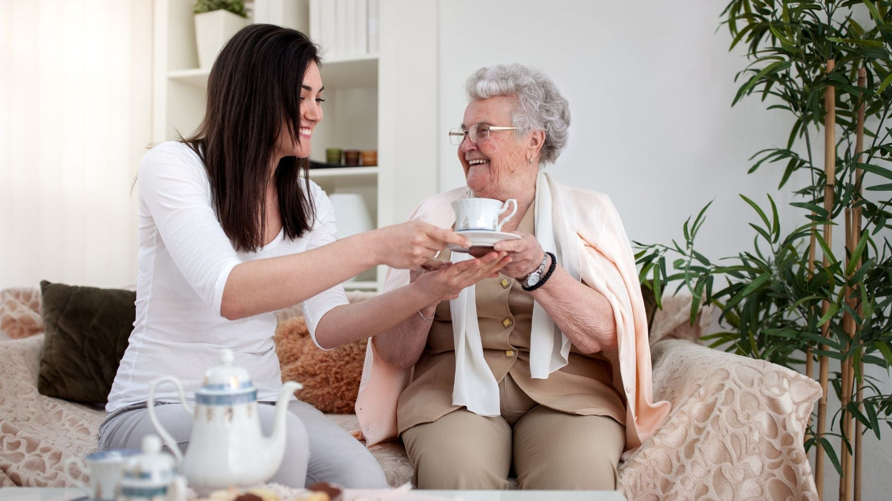 Woman serving tea to an elderly woman in a cozy living room