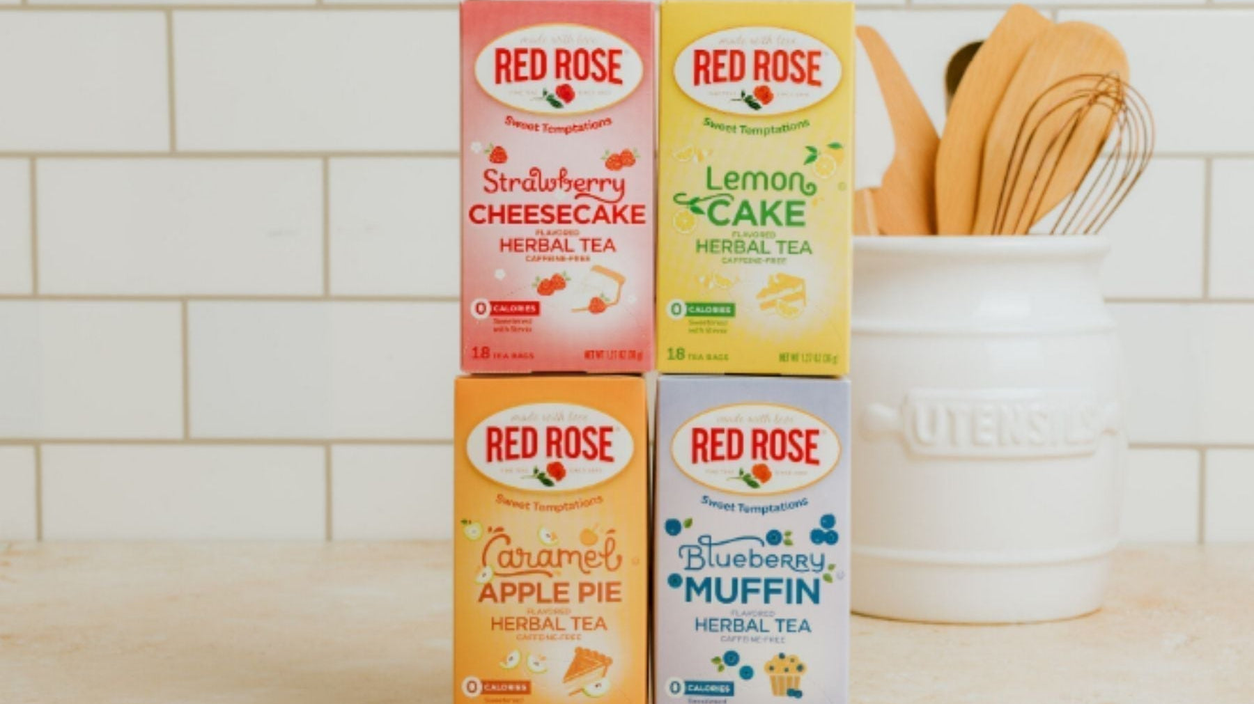 Assorted Red Rose herbal tea boxes (strawberry cheesecake, lemon cake, caramel apple pie, blueberry muffin) displayed on a kitchen counter