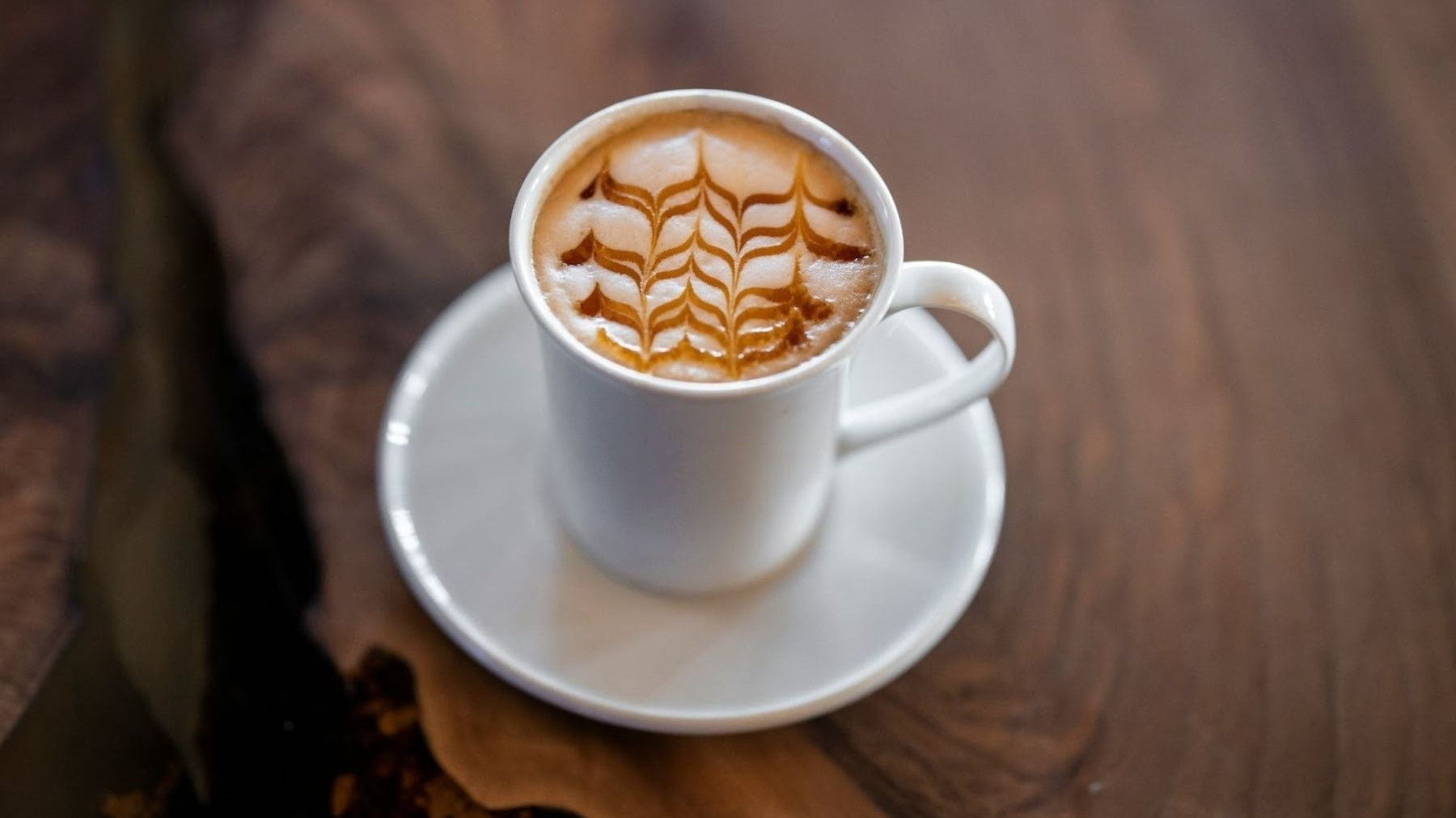 English Breakfast Tea Latte with an intricate foam design in a white mug.