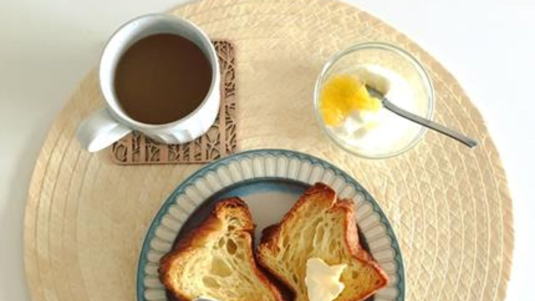 Overhead view of a butter-bread, english breakfast tea, and yogurt.
