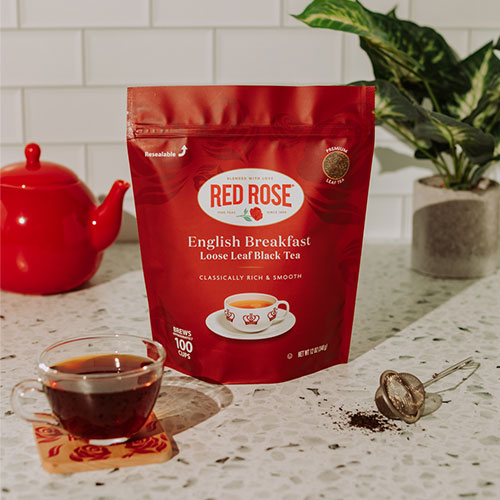 Red Rose English Breakfast tea package on a kitchen counter with a teacup and teapot.