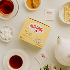 Red Rose Earl Grey Tea Bags at a tea table with sugar cubes, honey, and lemon slices