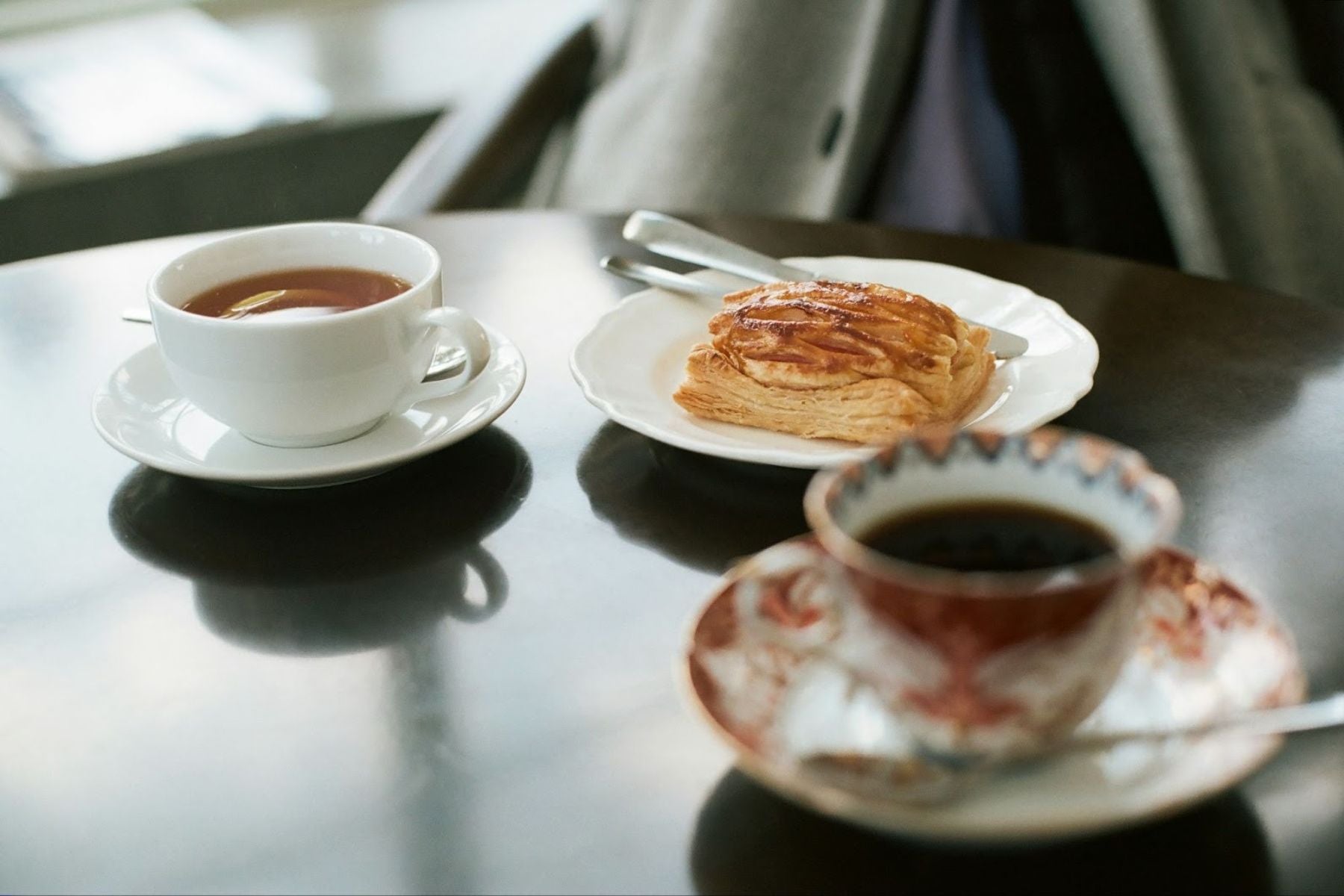 Two cups of English Breakfast tea served alongside a pastry