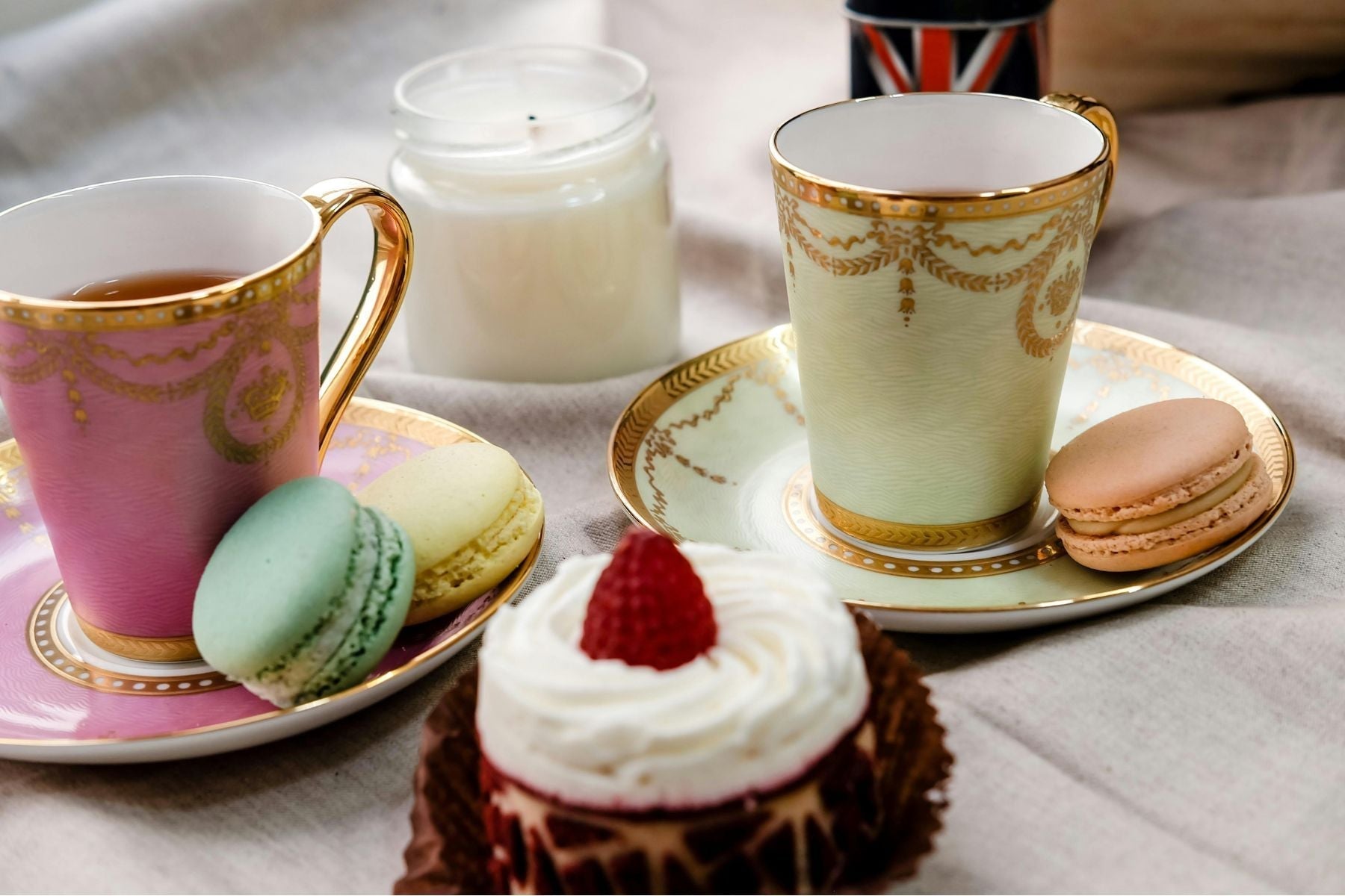 Elegant tea cups with macarons and cupcake in a cozy tea setting