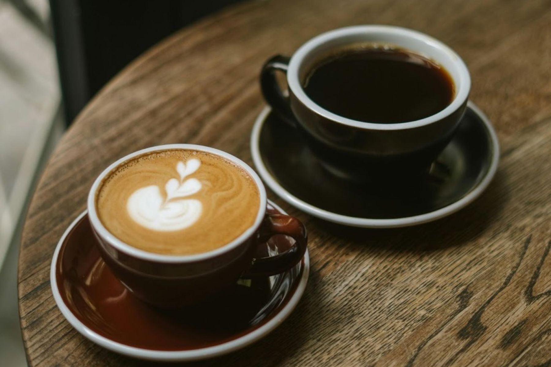 Coffee and black tea cups on a wooden table