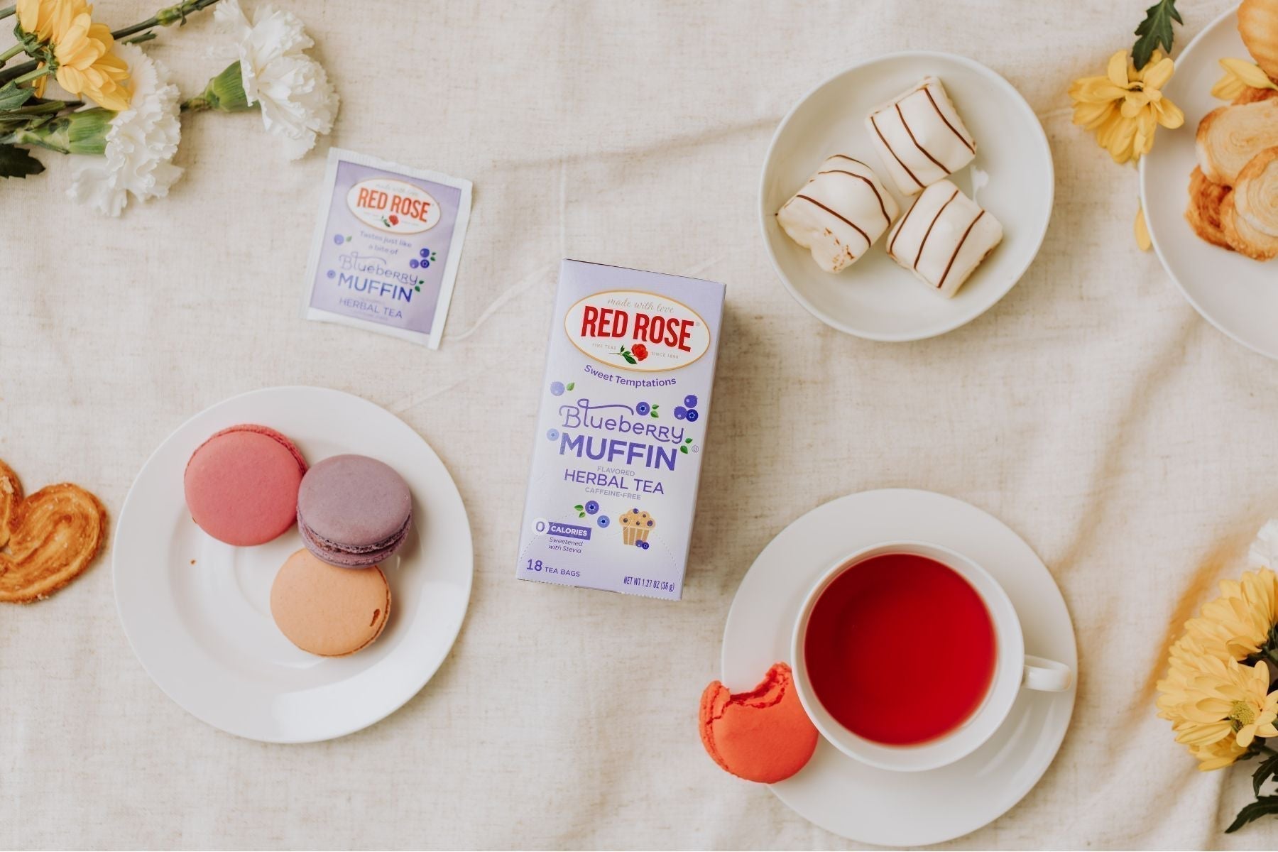Blueberry muffin tea box with macarons, pastries, and tea in a flat lay