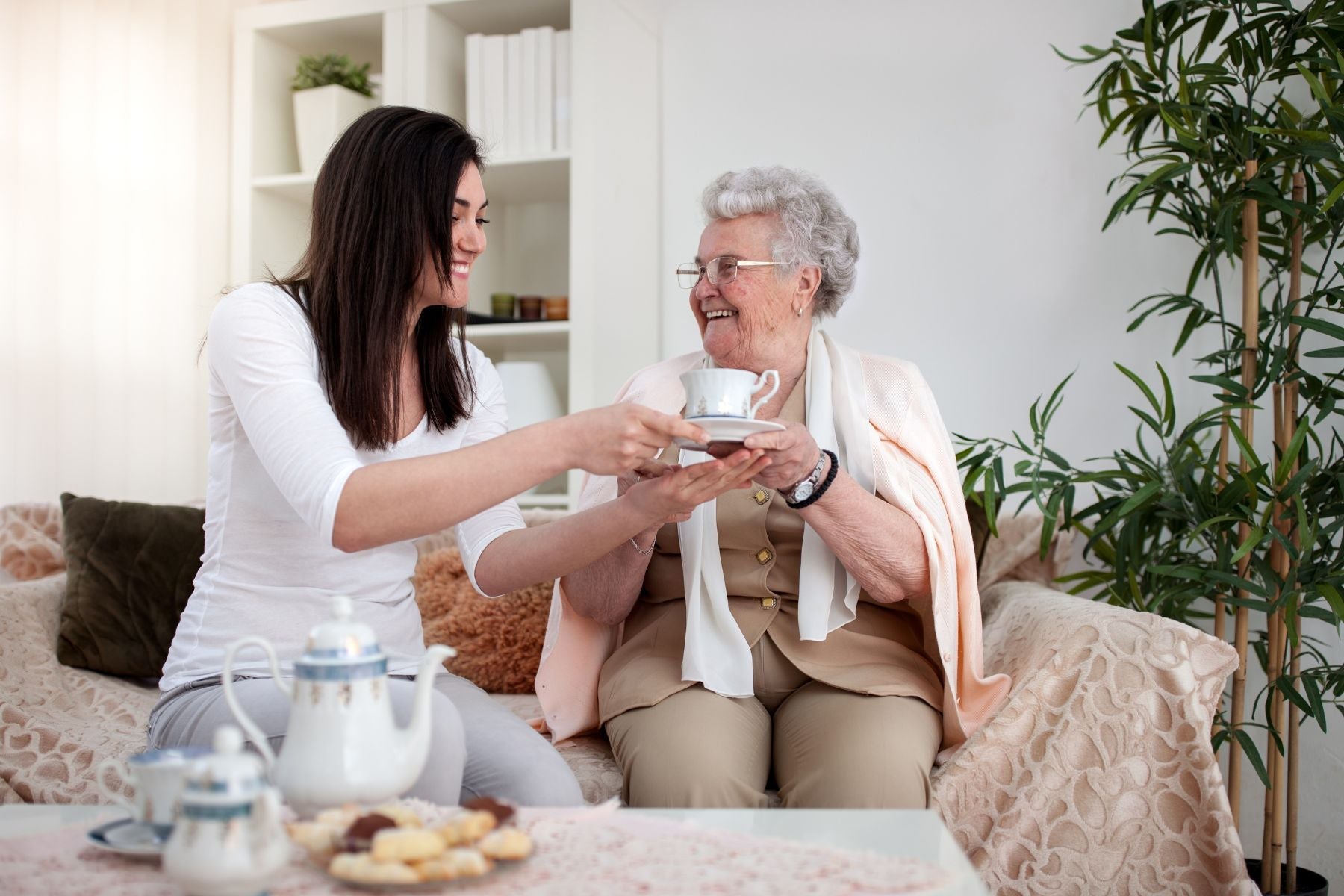 Woman serving tea to an elderly woman in a cozy living room