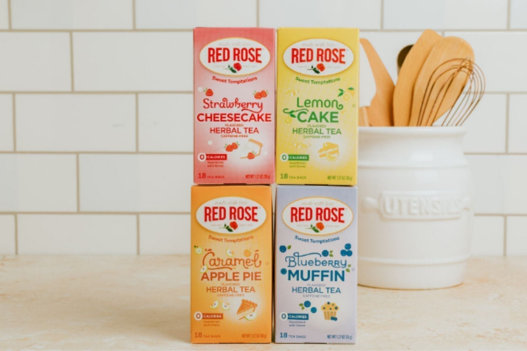 Assorted Red Rose herbal tea boxes (strawberry cheesecake, lemon cake, caramel apple pie, blueberry muffin) displayed on a kitchen counter