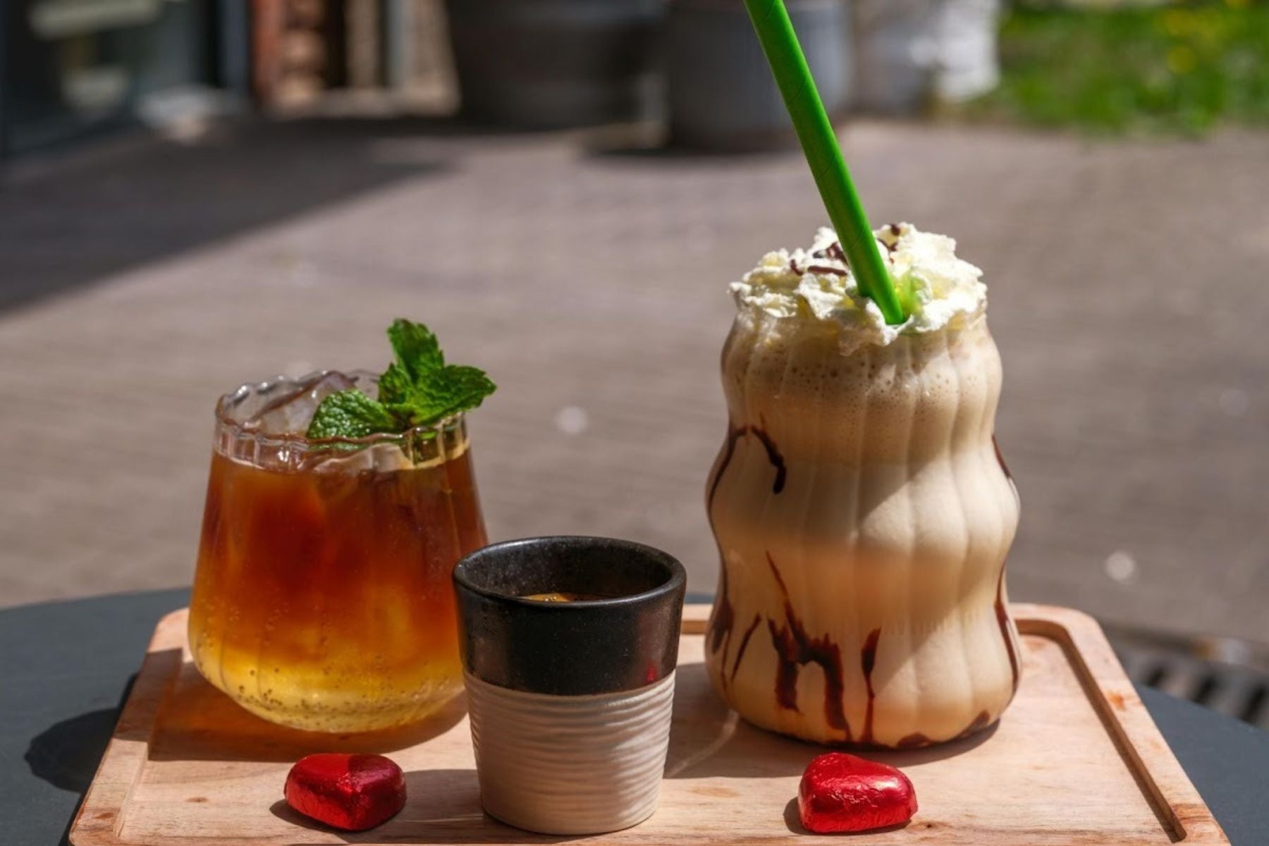 Iced tea and creamy milkshake-style drink with chocolate drizzle and whipped topping on a wooden tray