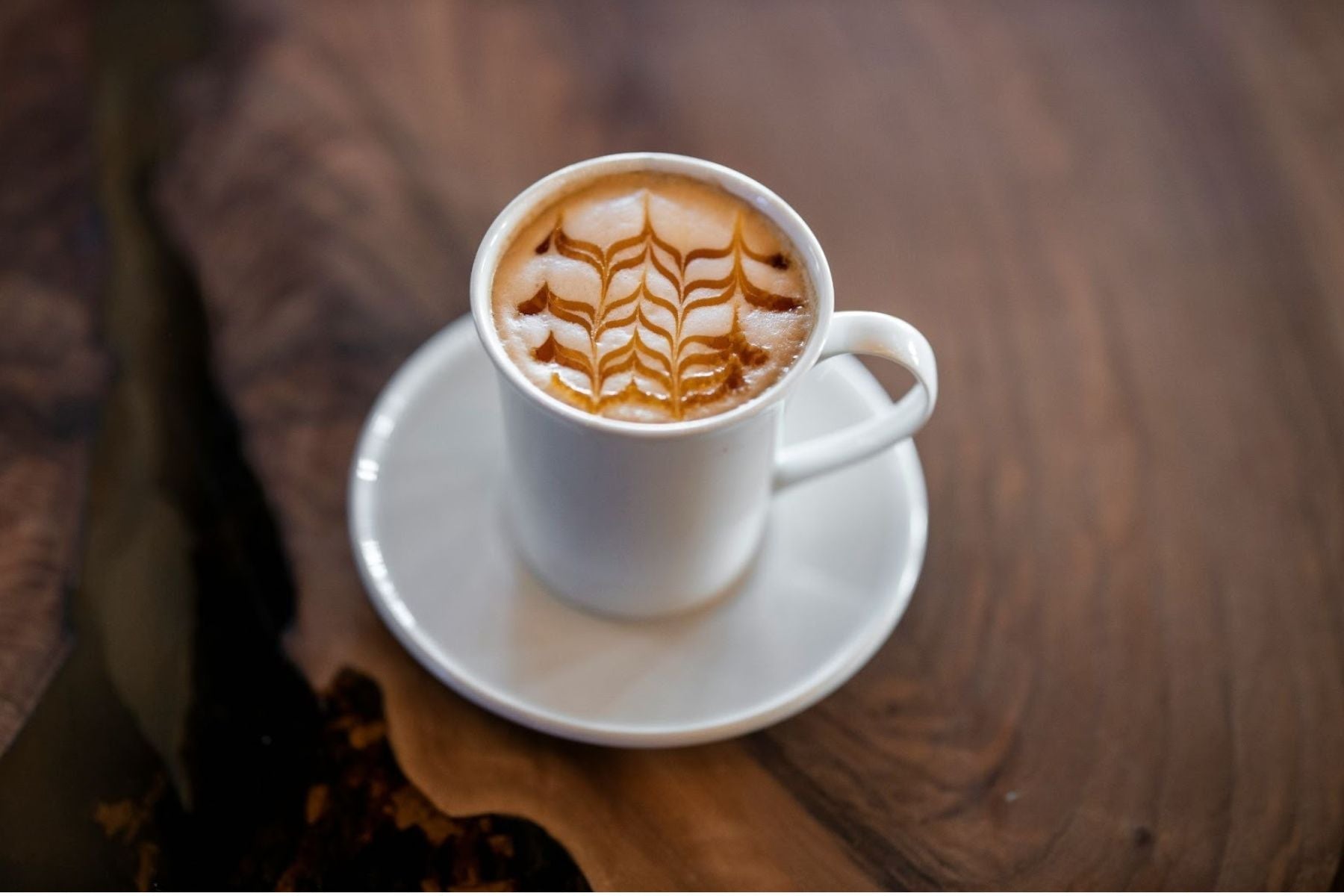 English Breakfast Tea Latte with an intricate foam design in a white mug.