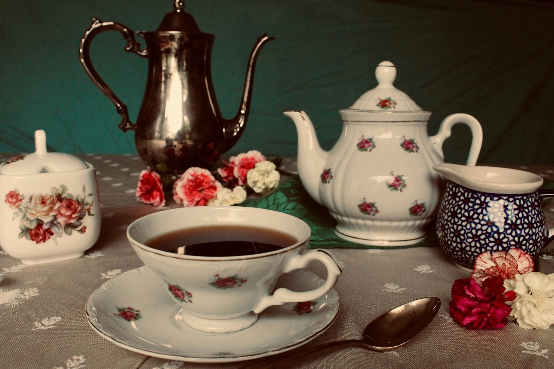 Vintage silver and floral china tea set arranged with a cup of black tea.