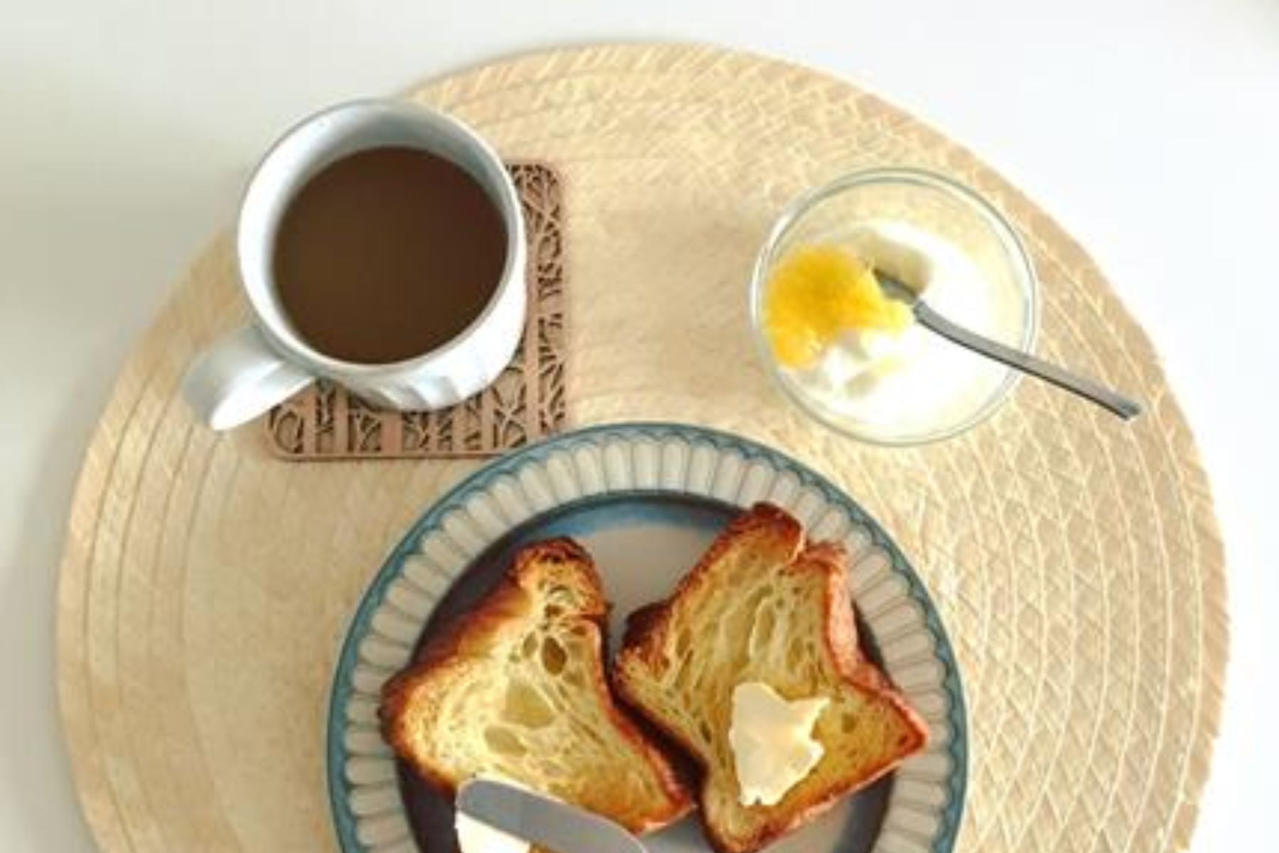 Overhead view of a butter-bread, english breakfast tea, and yogurt.