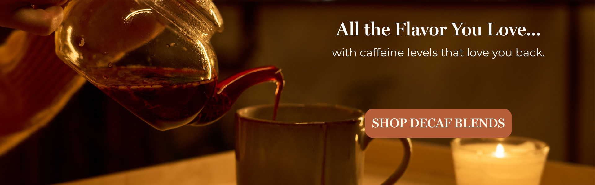 A warm, cozy scene showing a hand pouring tea from a glass pitcher into a mug, with a lit candle in the background. Large text reads 'All the Flavor You Love. with caffeine levels that love you back. Shop Decaf Blends.