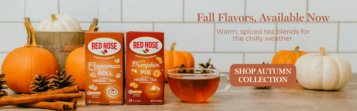 Red Rose tea products displayed with pumpkins, cinnamon sticks, and a cup of tea on a tabletop in a fall-themed setting. Visible products include Red Rose Cinnamon Roll and Red Rose Pumpkin Pie tea boxes, with promotional text reading 'Fall Flavors, Available Now' and 'Shop Autumn Collection.