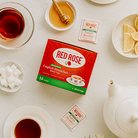 Red Rose Decaf English Breakfast Tea at a tea party table with sugar cubes, honey, and lemon